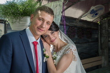 Bride and groom in a summer outdoor cafe under the green leaves of a tree.