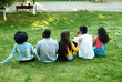 © etonastenka - Multi-ethnic friends are sitting on the grass in the park