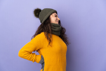 Teenager Russian girl with winter hat isolated on purple background suffering from backache for having made an effort