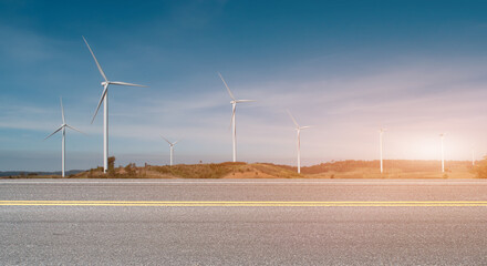 Wall Mural - Asphalt road with wind turbines at sunset background