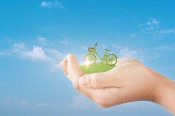 Canvas Print - hand holding green ecological bicycle over blue sky background. environmentally friendly concept.