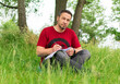 © bogdan vacarciuc - A man in the park, sitting in the grass and writing with a pen in an agenda.
