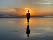 Silhouette of the person in the beach at sunset. A Woman walking alone toward the sun. Fragility concept. Strength and close to the light concepts on beach nature landscape background.