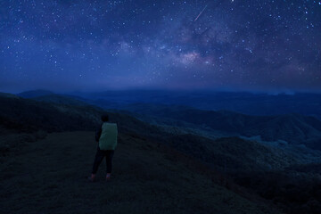 Wall Mural - colorful night sky with stars and silhouette of a standing man on the stone. blue milky way with man