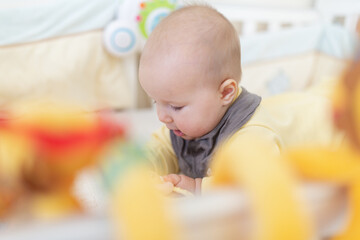 Canvas Print - Caucasian blonde baby five months old lying on bed at home. Kid wearing cute clothing trendy colors: ultimate gray and illuminating. Infant playing with toys