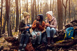 © Zoran Zeremski - Three female friends resting after hiking in forest sitting on collapsed trunk and drinking tea.