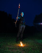 © ISliM - A guy dressed as Peter Pan stands with a burning torch against the night sky and dark forest