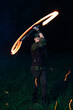 © ISliM - A guy in a Peter Pan costume twists a burning torch in his hands, which leaves a fiery trail, night against the dark forest