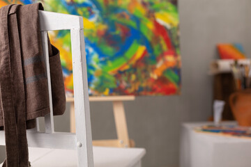 Poster - Oil painting and wooden chair with apron. Art still life and paintbrush in artist creative studio