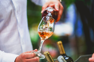 Wall Mural - The waiter serves rose, red and white wine from the wine bottle in the wine glass at an event.