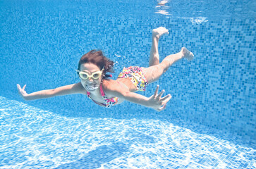 Fototapete - Child swims underwater in swimming pool, active girl dives and has fun under water, kid fitness and sport on family vacation 

