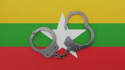 A half opened steel handcuff in center on top of the national flag of Burma (Myanmar)