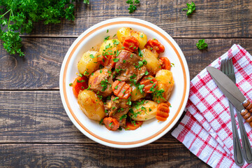 Wall Mural - Roast turkey, potatoes, carrots and fresh parsley in a bowl on a wooden background. Useful and nutritious dish. Top view.