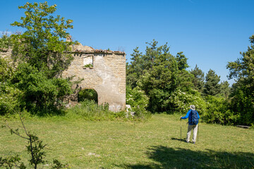 Man with backpack admiring  the ruins of old house in the countryside. Podere Montebello, Modigliana, Forlì, Emilia Romagna, Italy, Europe.