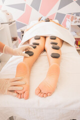 Wall Mural - Vertical shot of a Hispanic female getting a hot stone massage at a spa