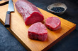 Traditional raw beef fillet steak natural with black salt as close-up on a modern design wooden board