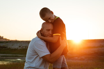 Wall Mural - Son and dad standing against the backdrop of a colorful sunset. The relationship between father and son. Family's soulful walk in nature in the rays of the setting sun