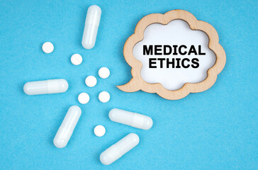 Wall Mural - On a blue background, pills and a plate, inside which the inscription - MEDICAL ETHICS