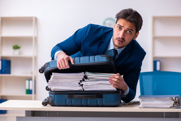 Young male employee preparing for business trip at workplace