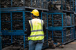 © NVB Stocker - Plus size black female worker wearing safety hard hat helmet inspecting old car parts stock while working in automobile large warehouse