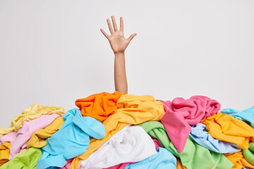 unrecognizable human raises arm reaches out heap of colorful unfolded clothes busy doing wardrobe cl