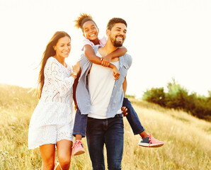 child daughter family happy mother father piggyback fun together girl cheerful field outdoor natur summer