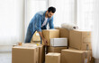 © Nopphon - Young man just moving new house. He unpacking parcel box and arranging on the floor in the living room.