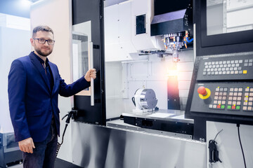 Modern process metal detail production going for car. Worker man entering data in CNC drill machine at automatic factory floor