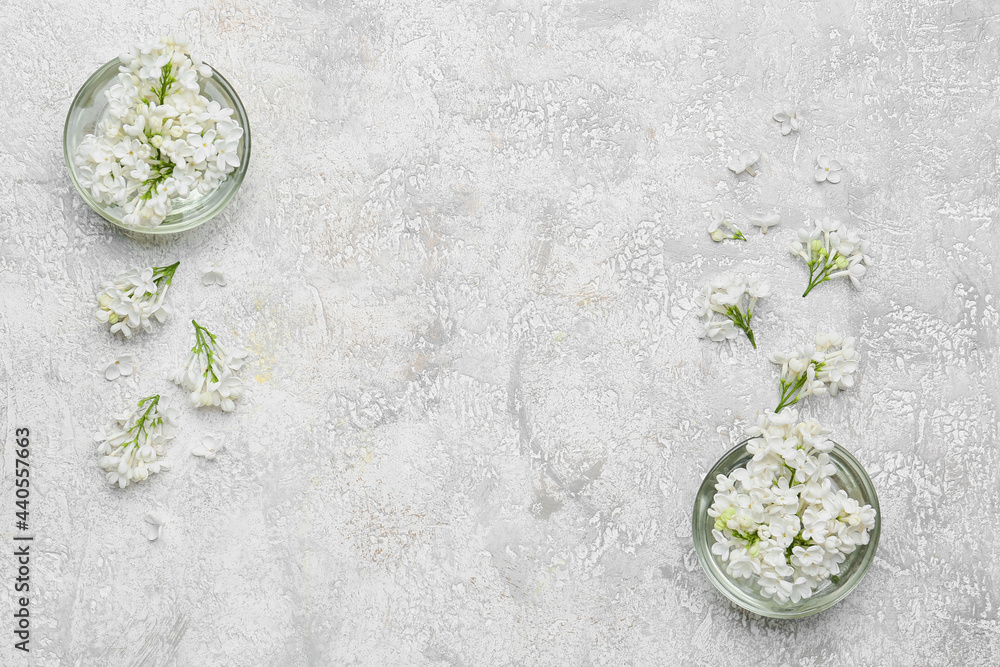 Bowls with beautiful lilac flowers on light background