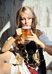 Wall Mural - Bavarian woman with glass of beer posing on light background. Oktoberfest 2021 concept.