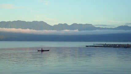 Wall Mural - Beautiful landscape of Maninjau Lake, Indonesia at golden hour in the morning with a fishing boat sailing over. The landscape of West Sumatra, Indonesia nature.