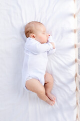 healthy sleep of a newborn baby in a cot in a bedroom on a cotton bed, top view