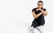 © Liubov Levytska - A sporty woman in sportswear is sitting on the floor. Sport and recreation concept. Fitness athlete girl resting in studio after workout, exercises or jogging, smiling pleased