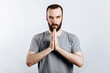 © Daria Lukoiko - A man with crossed palms. The guy reads a prayer with his palms crossed in front of him. Portrait of handsome young man n white background with space for advertising mock up