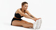 © Liubov Levytska - Athlete doing stretching exercises in fitness studio white background. Woman runner stretching leg muscles by touching her shoes, workout training session in activewear