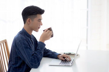 Young business man working from home with laptop computer on desk, freelance male sitting stay home using notebook for communication and relax on table, entrepreneur in startup business, new normal.