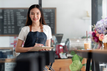 Young beautiful entrepreneur working at her coffee shop, serving for her customer.