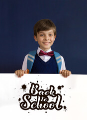 Close-up of a smiling, laughing, happy, funny teenage boy showing isolated on blue background. lettering Back to school