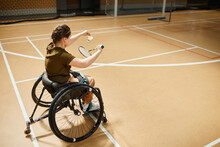 High Angle Portrait Of Young Woman In Wheelchair Playing Badminton During Sports Practice At Indoor Court, Copy Space