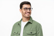 Close-up portrait of young handsome smiling man wearing casual green shirt and glasses, looking away isolated on gray background