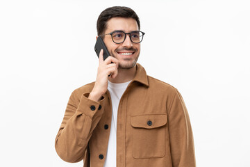 portrait of handsome young man in brown shirt and glasses, answering phone call, looking aside with 