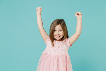 Wall Mural - Little fun cute kid girl 5-6 years old wears pink dress doing winner gesture say yes isolated on pastel blue color background child studio portrait. Mother's Day love family people lifestyle concept.