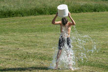 Teenage Boy Pouring Bucket Of Cold Water Over His Head Outdoors. Ice Water Challenge. Cold Water Therapy Benefits