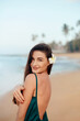 © verona_studio - Young smiling woman looking at camera on the beach. Portrait of beautiful girl with ocean in background.