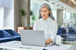 © insta_photos - Serious focused Asian older businesswoman executive manager sitting at desk working typing on pc laptop computer in contemporary corporation office. Business technologies career concept.