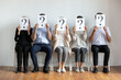 © fizkes - Diverse job candidates hiding faces behind sheets with question marks, sitting on chairs in row, business people waiting for job interview, human resources, employment and recruitment concept