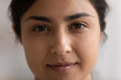 Crop close up portrait of young Indian woman with healthy skin, no makeup natural face look. Smiling millennial mixed race ethnicity female renter tenant look at camera. Diversity concept.