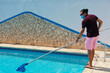 Man with protective mask cleaning the pool