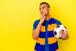 Young venezuelan man watching soccer isolated on yellow background looking sideways with doubtful and skeptical expression.