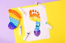 New Trendy Popular Silicone Colorful Anti Stress Pop It Toy For Child And Colorful Footprint On Colorful Background.